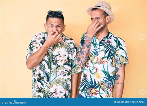 Joven Pareja Gay De Dos Hombres Con Sombrero De Verano Y Camiseta Hawaiana Oliendo Algo Afilado