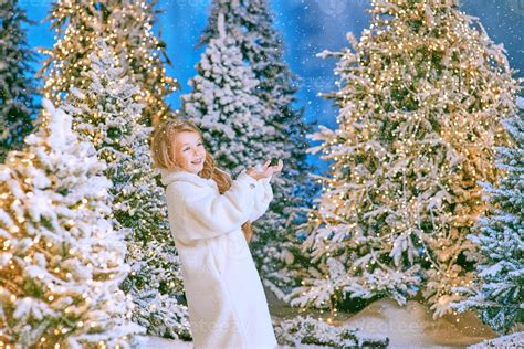 jolie fille blonde caucasienne en manteau de fourrure écologique blanc marchant dans la forêt de