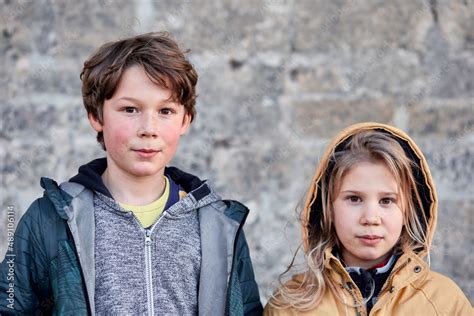 Foto de Portrait d un frère et d une soeur blonde sérieuse sur fond de mur ancien do Stock
