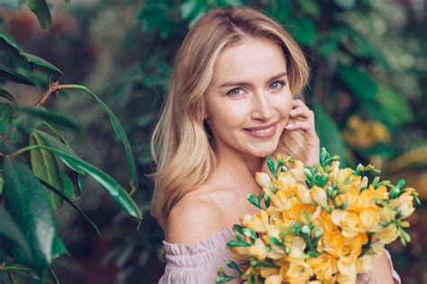 Gros plan de jeune femme blonde à bouquet fleur jaune Photo Gratuite