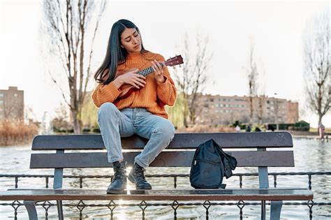 Jovem Latina Tocando Ukulele Em Uma Mulher Do Parque Da Cidade Sentada Em Um Banco Praticando