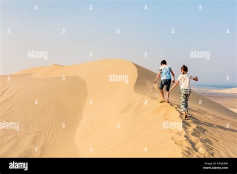 Kids Having Fun Playing Together At Sand Dunes In Qatar Desert Stock
