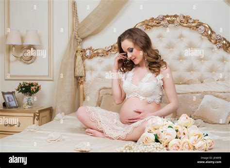 Beautiful Pregnant Brunette Sitting On A Bed In The Lotus Position Stock Photo Alamy