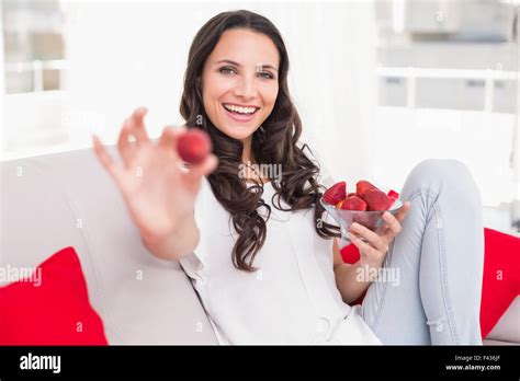 Pretty Brunette Eating Strawberries On Couch Stock Photo Alamy