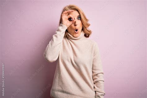 Middle Age Beautiful Blonde Woman Wearing Casual Turtleneck Sweater Over Pink Background Doing