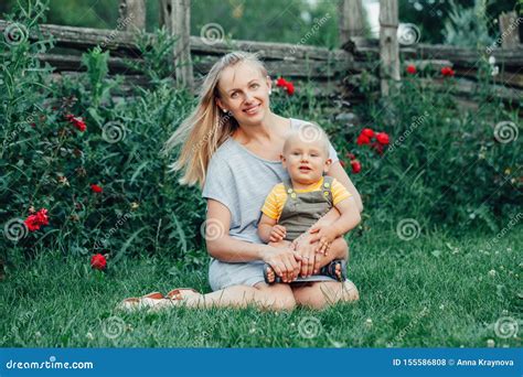 Caucasian Ukrainian Mother With Long Blonde Hair In Blue Dress Holding
