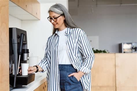 Happy White Haired Mature Woman Smiling While Using Coffee Maker Stock Photo Image Of Pleased