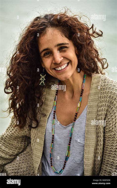 A Beautiful Latina Woman With Long Brown Curly Hair Smiles Naturally Into The Camera She Is