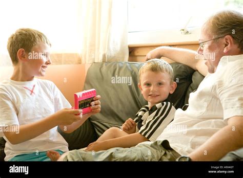 A Blonde Man With His Two Sons Sitting On A Couch At Home Stock Photo