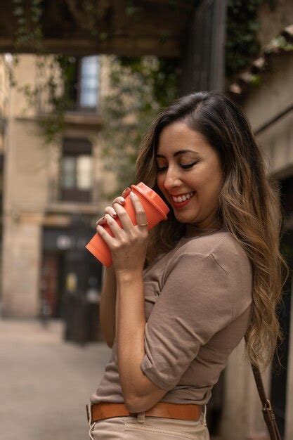 Hermosa mujer adulta joven latina de pelo largo sonriendo alegremente mientras toma un café para