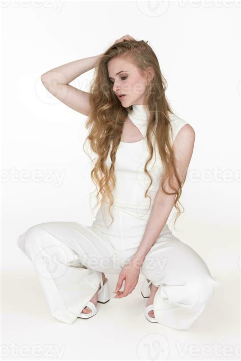 Woman sits squatting position, looking down, raised one hand behind