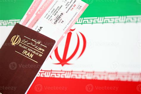 Red Islamic Republic Of Iran Passport With Airline Tickets On Iranian Flag Background Close Up