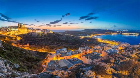 Skyline view of Mellieħa town after sunset with Parish Church and beach ...