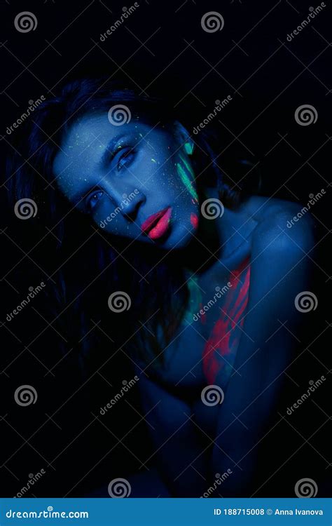 Nude Woman In Neon Light UV Paint On The Woman Face And Body Perfect Figure And Breasts Of A