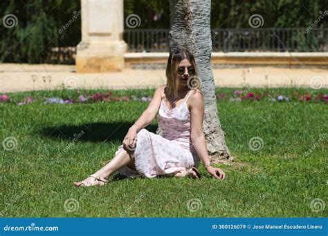 Jovem Loira E Latina Sentada Na Sombra Ao Lado Do Tronco De Uma Palmeira No Parque Fazendo