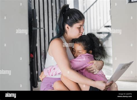 belle latina femme embrassant sa fille en lisant la lettre que sa fille lui a donné comme cadeau