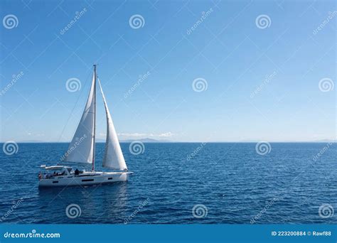 Sailing Boat With Open White Sails Blue Sky And Rippled Sea Background