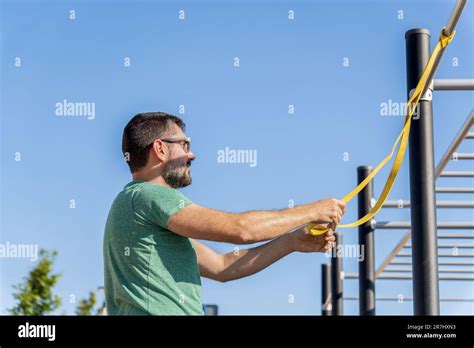 Bearded Man With Sunglasses Seen In Profile Training With An Elastic