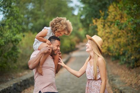 Fröhliche junge blonde Ehefrau und afroamerikanischer Ehemann mit einer kleinen kraushaarigen