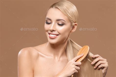 Beautiful Blonde Nude Woman Combing Long Hair Isolated On Brown Stock Photo By Lightfieldstudios