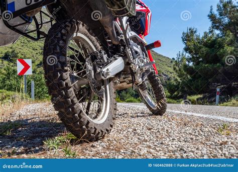 A Red Enduro Motorcycle Parked On The Gravel Road On The Side Of The