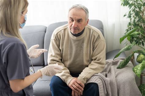 Portrait Of Mature Female Psychiatrist Interviewing Handicapped Senior Man During Therapy