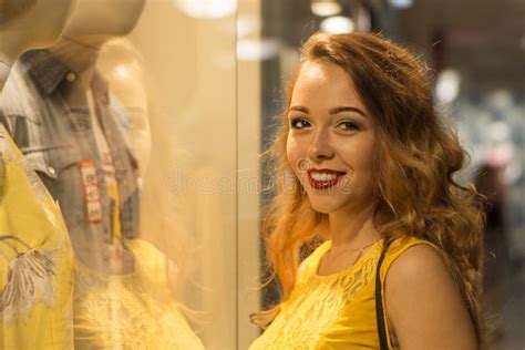 La Jeune Fille De Sourire Attirante Dans La Robe Jaune Goûte Le Parfum