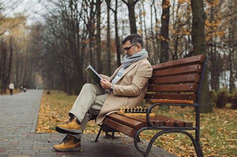 Un Vieil Homme Lit Un Magazine Assis Sur Un Banc Dans Un Parc En