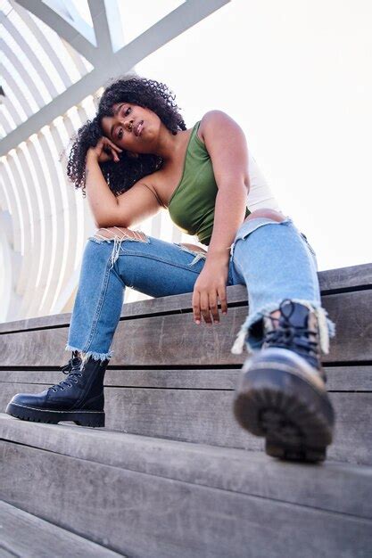 Atractiva Chica Latina Alegre Y Rizada Posando Al Aire Libre Sentada En Un Banco Concepto De
