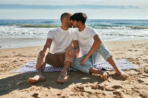 Joven Pareja Gay Besándose Sentado En La Playa Foto de archivo Imagen de gente alegre