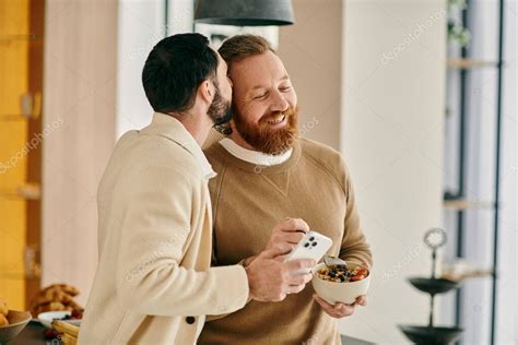 Dos hombres barbudos una feliz pareja gay están disfrutando del desayuno juntos en una cocina
