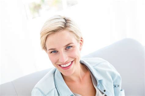 Premium Photo Pretty Blonde Woman Sitting On The Couch And Smiling At The Camera