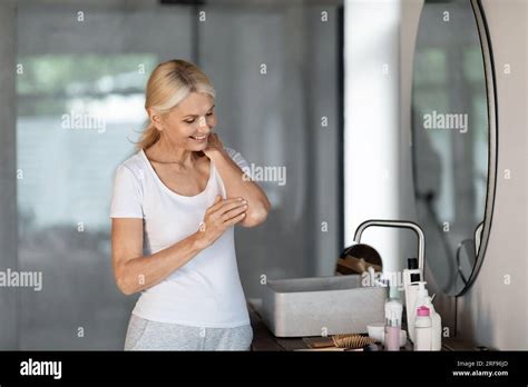 Body Care Concept Smiling Mature Female Rubbing Moisturising Lotion On Elbow Stock Photo Alamy