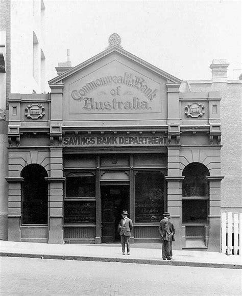 Two Men Are Standing In Front Of An Old Bank With The Words Australia On It