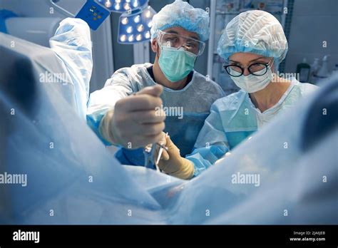 Two Surgery Professionals Making Operation In Pelvic Area Stock Photo