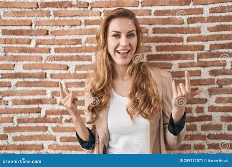 Belle Femme Blonde Debout Sur Des Briques Mur Crier Avec Une Expression Folle Faire Rock Symbole