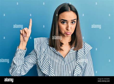 Jeune fille étudiante brunette pointant vers le haut avec le doigt déprimé et s inquiéter de la