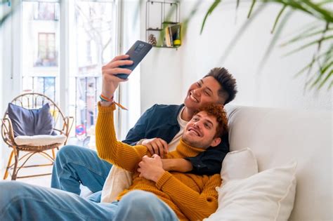 Lindo casal gay sendo romântico em casa no sofá tomando um conceito selfie lgbt Foto Premium