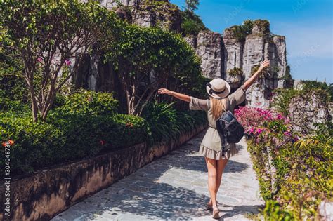 Beautiful Excited Blonde Woman Backpacker Walks And Admires Tropical Landscapes At Paradise