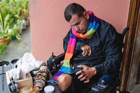 Horizontal Image Of A Disabled Gay Latino Man In An Electric Wheelchair Using His Cell Phone To