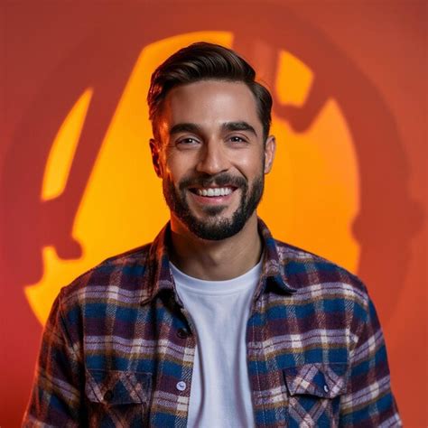 A Man Wearing A Plaid Shirt Smiles In Front Of A Yellow Background