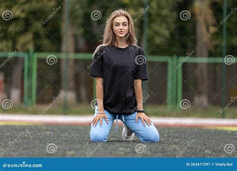 Slim Blonde Woman In Sportswear Posing On The Football Field Kneeling