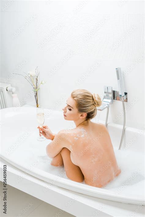 Beautiful And Naked Woman Taking Bath And Holding Champagne Glass In