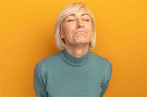 Femme Slave Jolie Blonde Insatisfaite Se Tient Avec Les Yeux Fermés Isolé Sur Mur Orange Photo