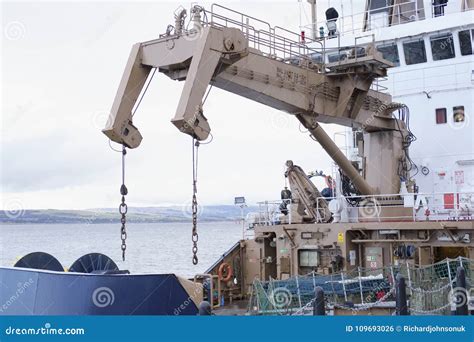 Crane On Large Ship Lifting Cargo To Transport On Boat Stock Photo