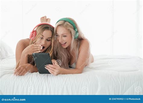 Two Caucasian Girls Wear Bikini On The Bed Playing With Tablet And