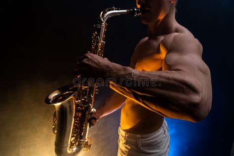 Muscular Man With Naked Torso Playing On Saxophone With Smoked Colorful Background Stock Photo