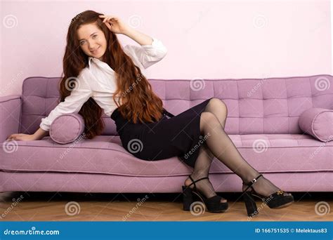 Beautiful Woman With Long Red Hair Sitting On A Sofa Stock Image