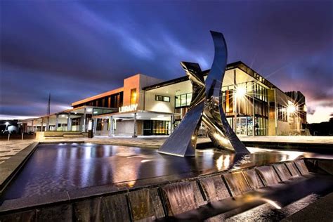 a large building with a fountain in front of it at night, and lights ...