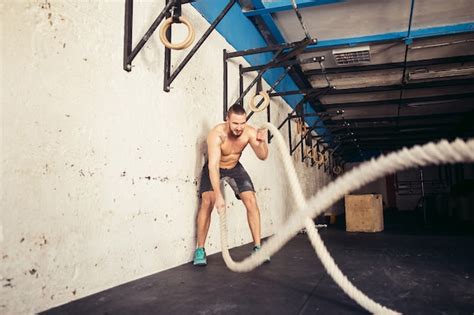 Premium Photo Man With Battle Ropes Exercising In Fitness Gym